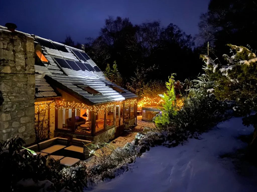Outside of large Highland lodge with snow and Christmas lights for New Year